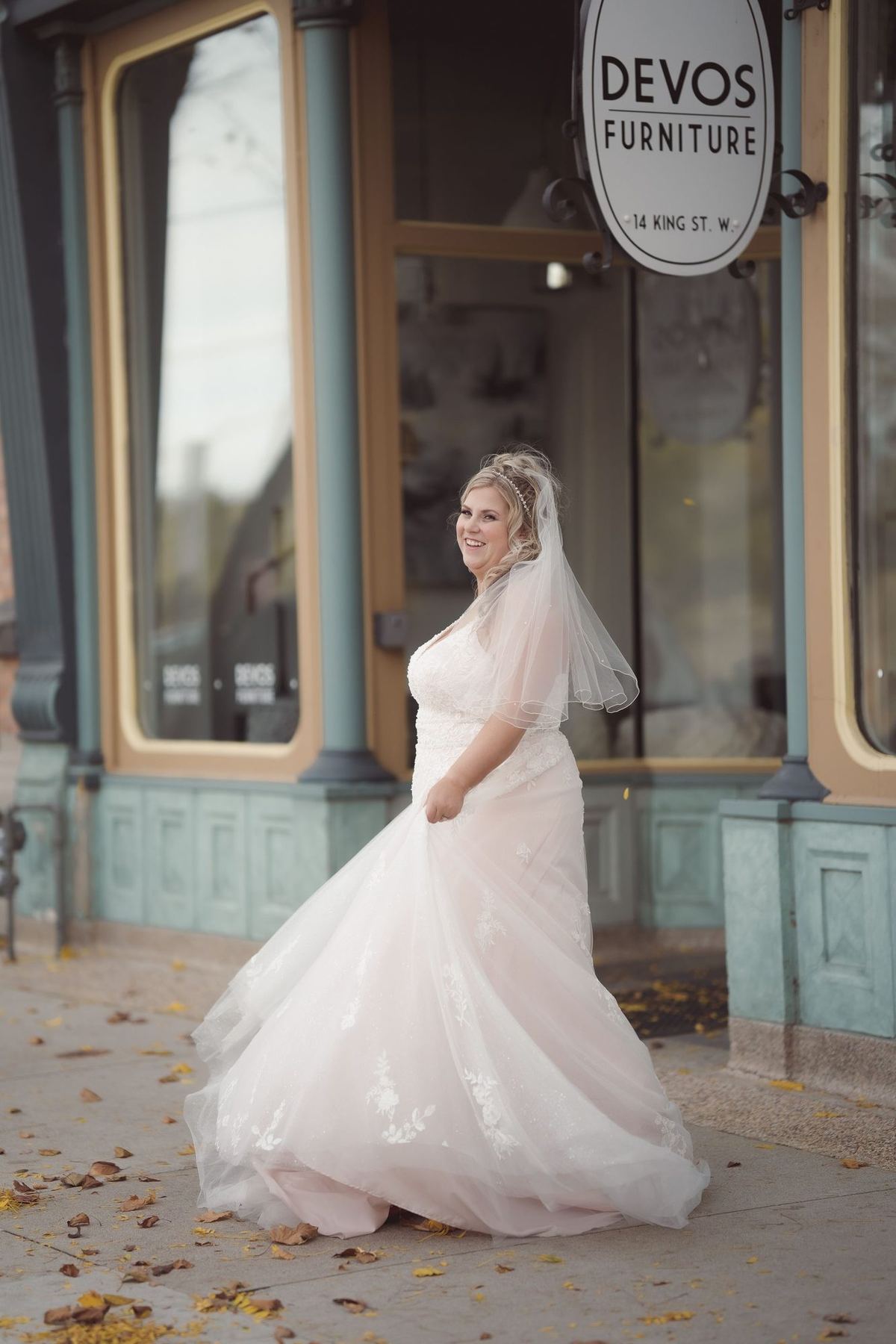 Bride in a full gown standing on a downtown sidewalk in autumn