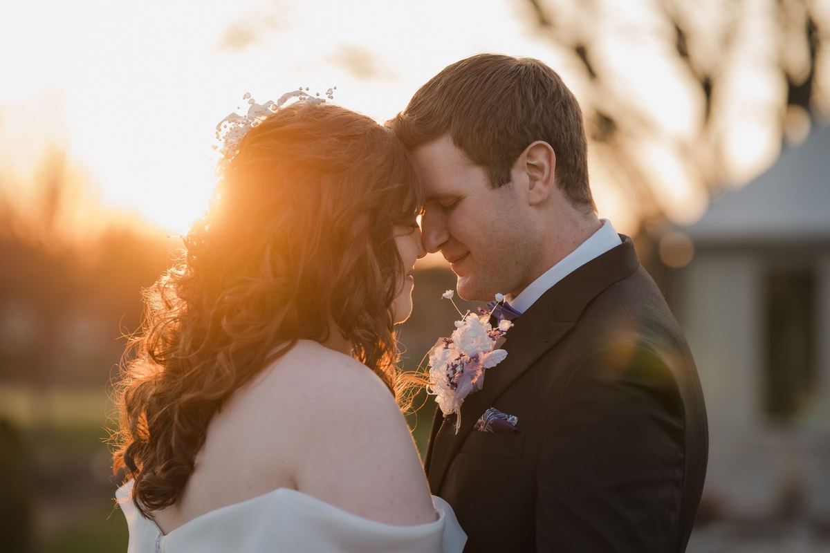 Bride and groom touching foreheads with the sun setting behind them at Links of Kent