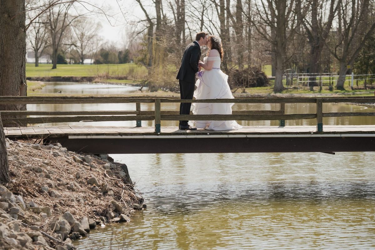 Bride and groom on a small bridge over a pond at Links of Kent Golf Club