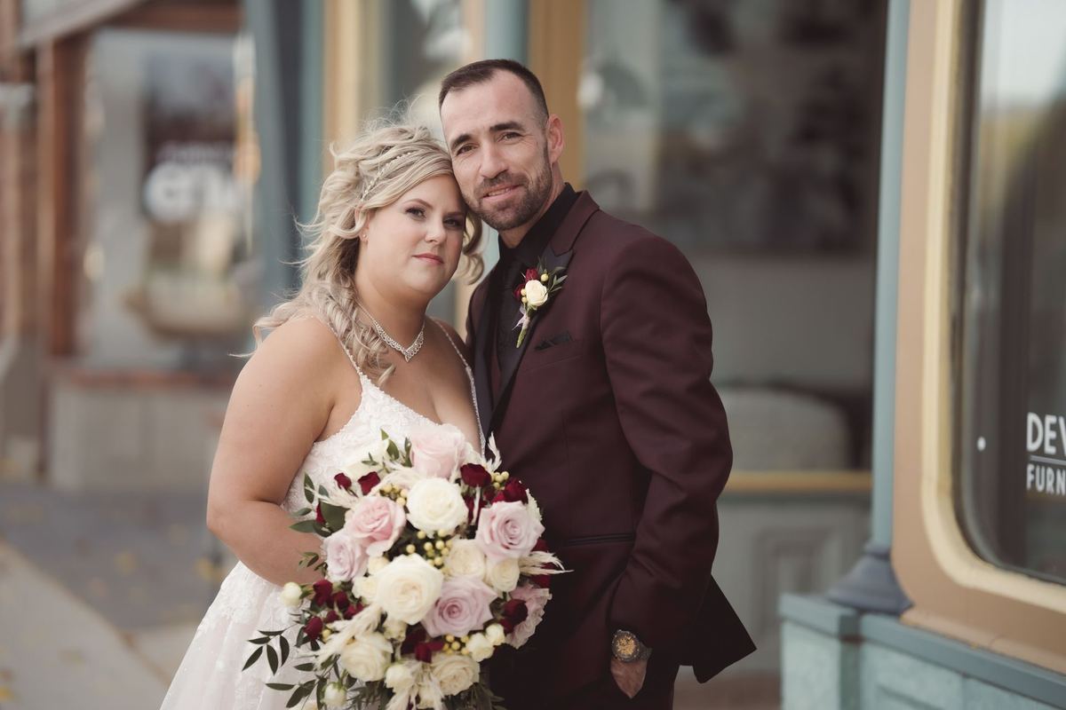 Bride and groom posing together in front of a downtown storefront
