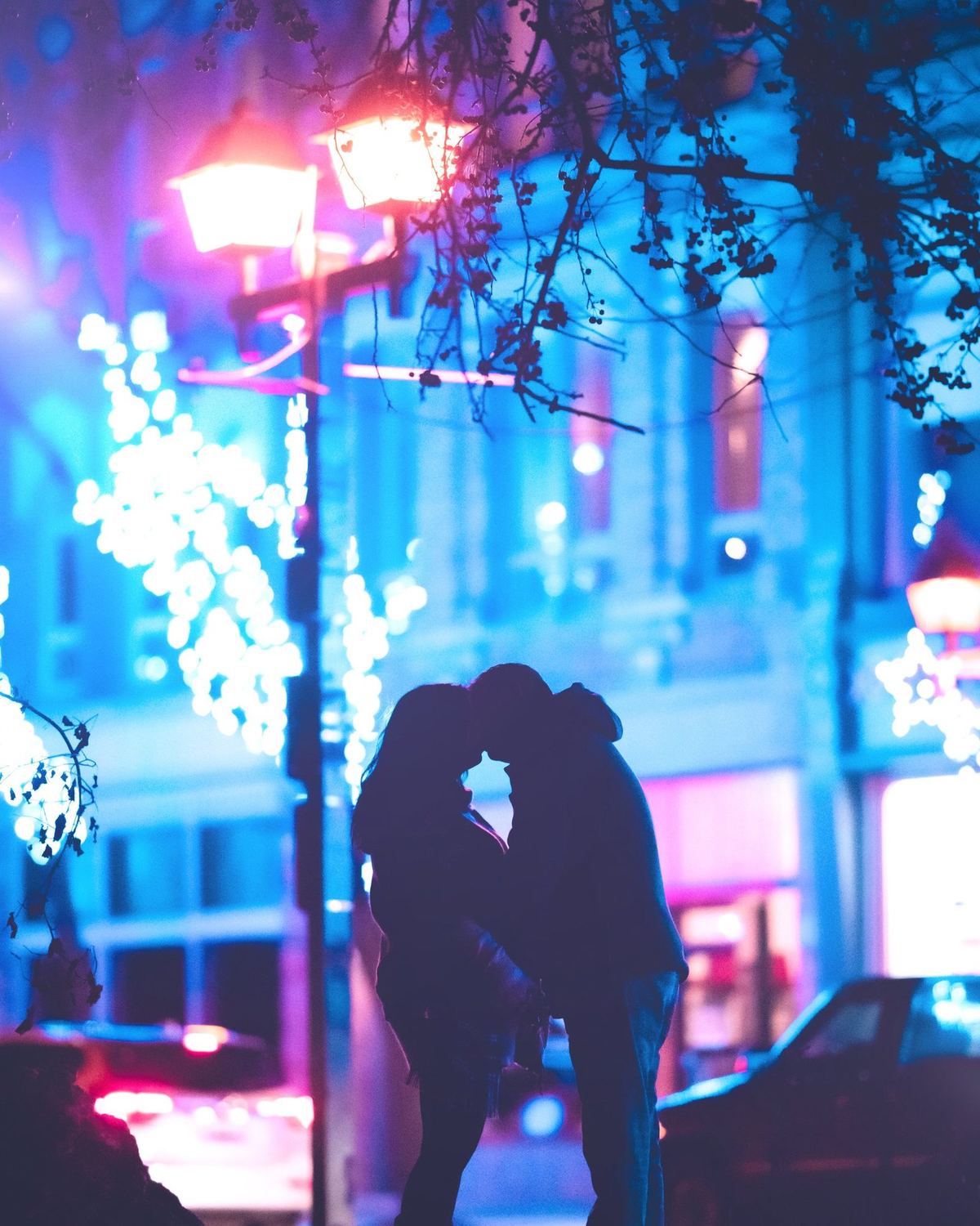 Couple kissing in silhouette under glowing street lamps and neon in a backlit night wedding portrait