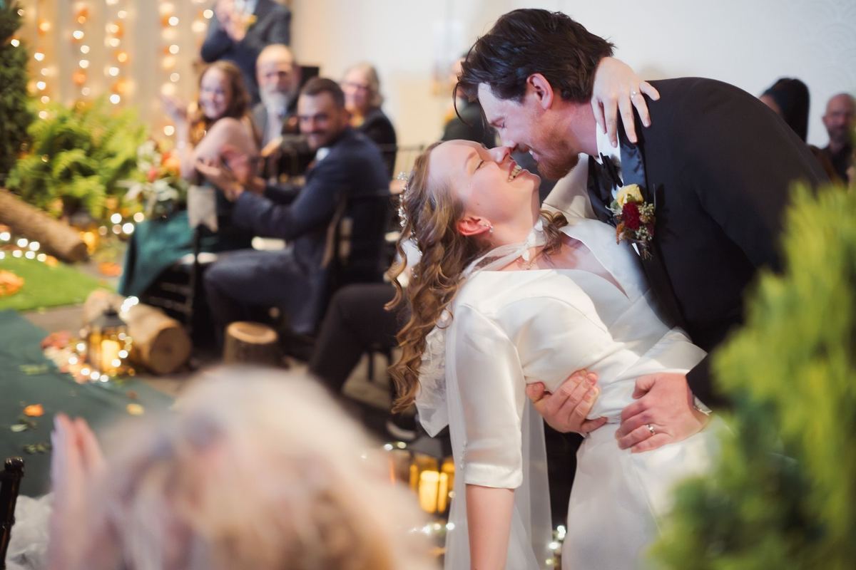 Groom dipping the bride for a kiss in the aisle as guests cheer