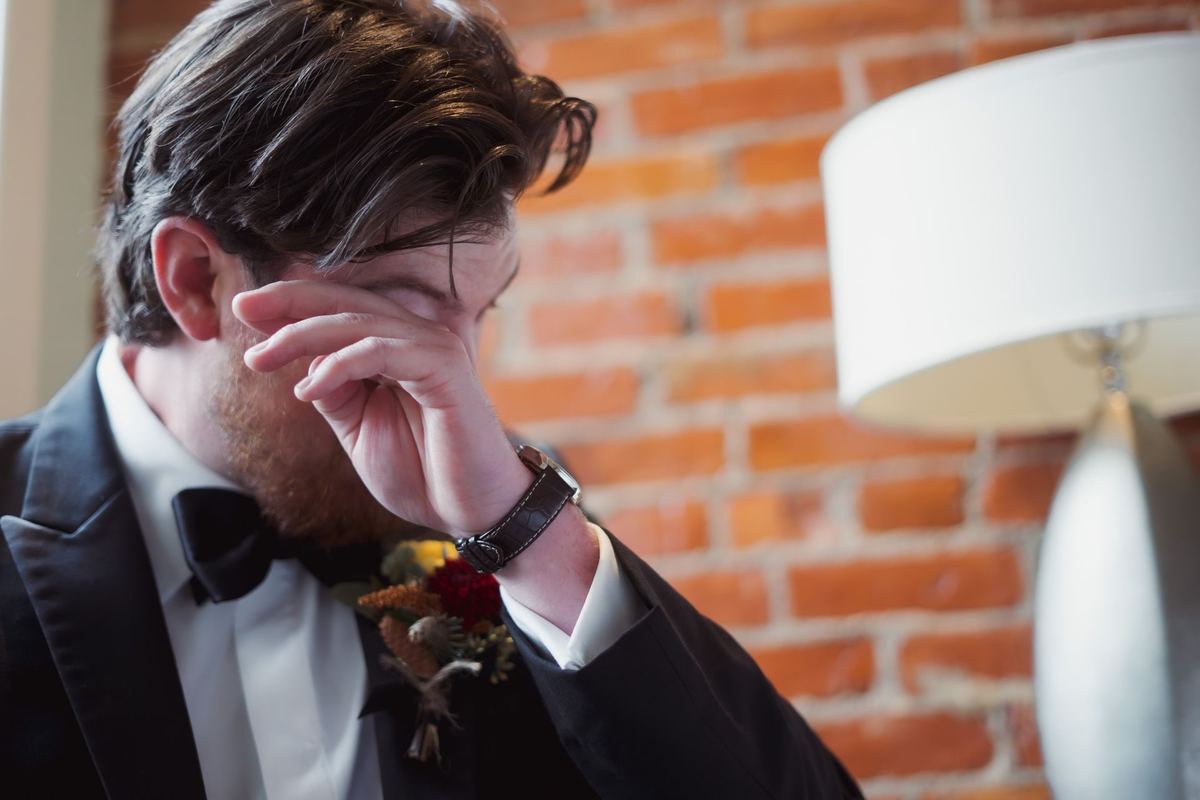 Groom wiping a tear while reading a letter on his wedding day