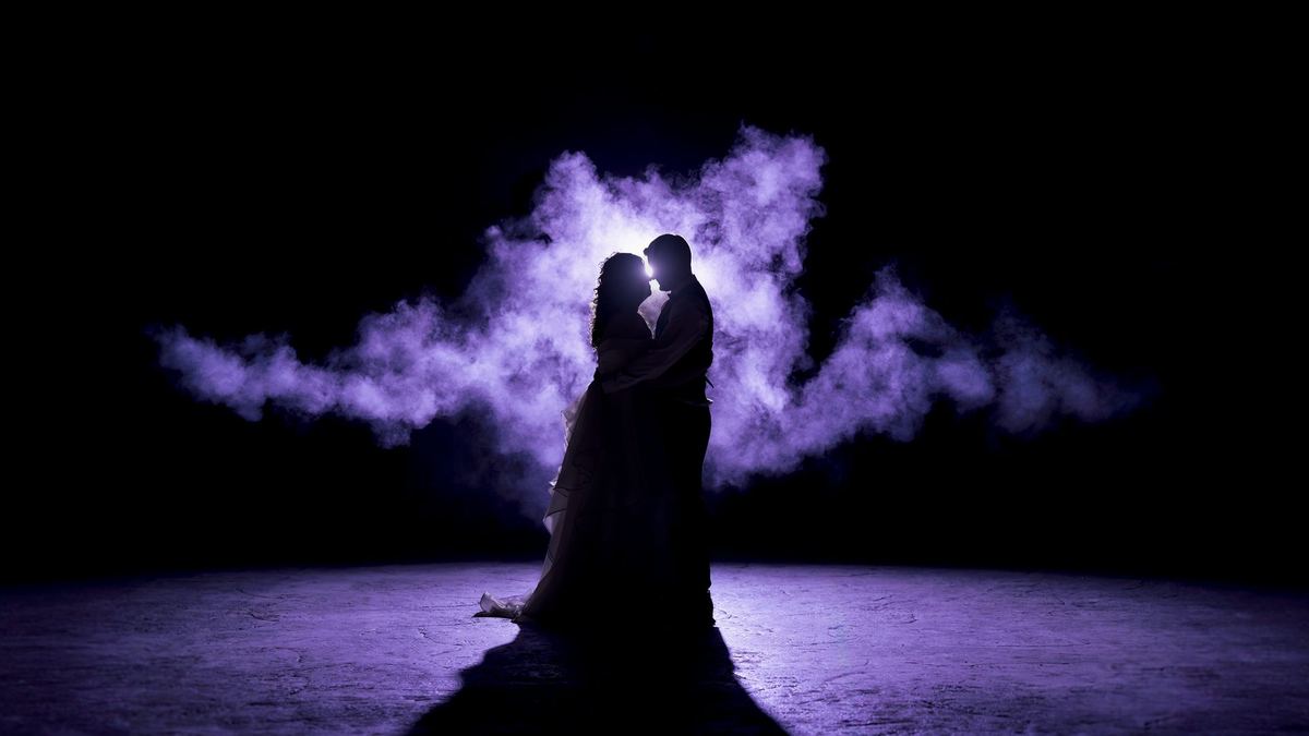 Newlyweds silhouetted by purple-lit smoke in an end-of-night backlit wedding portrait at Links of Kent
