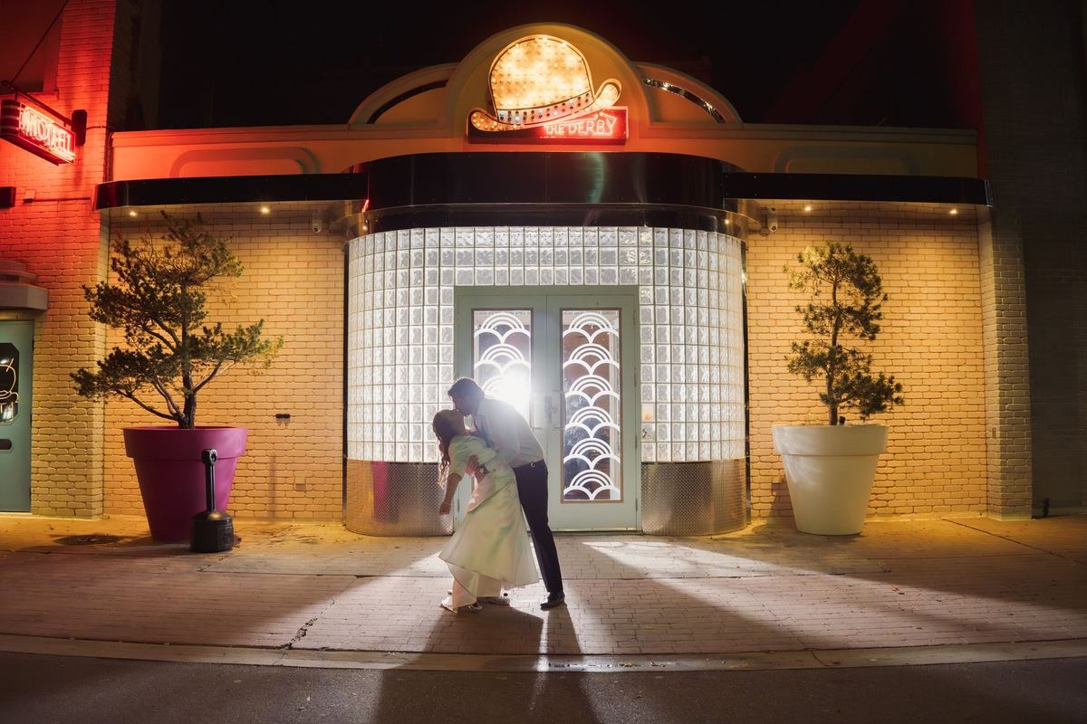 Couple kissing in the lit doorway of the Retro Suites Hotel in an end-of-night backlit wedding portrait