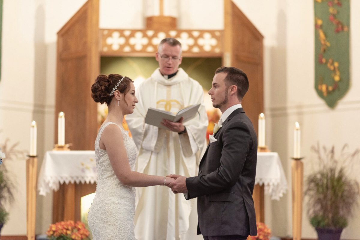 Bride and groom facing each other at the altar as the officiant leads their vows