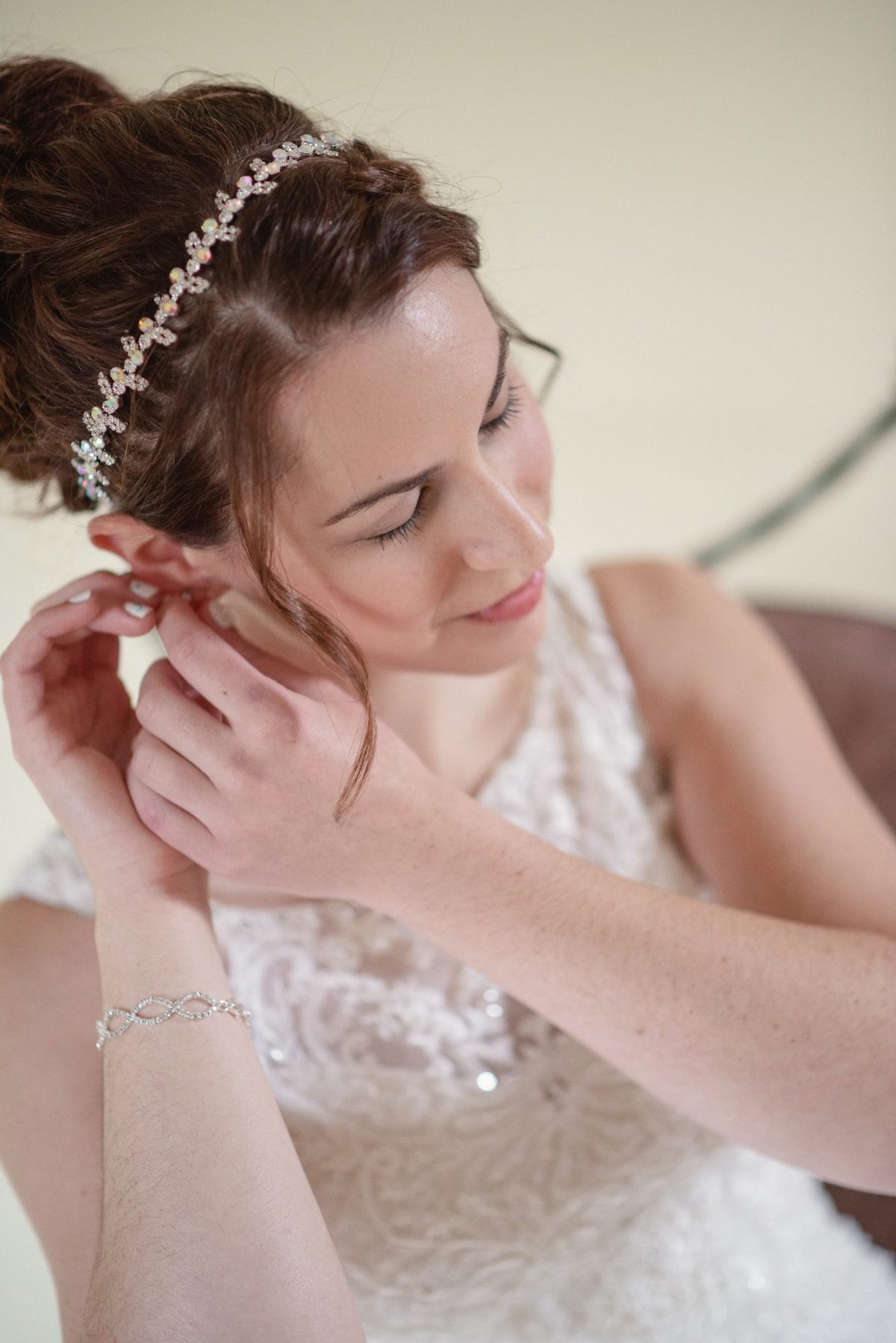 Bride in a jewelled headband fastening her earring