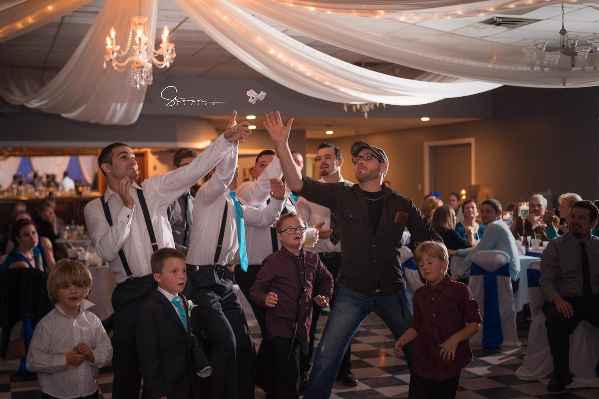 Guests cheering and dancing together on a packed reception dance floor
