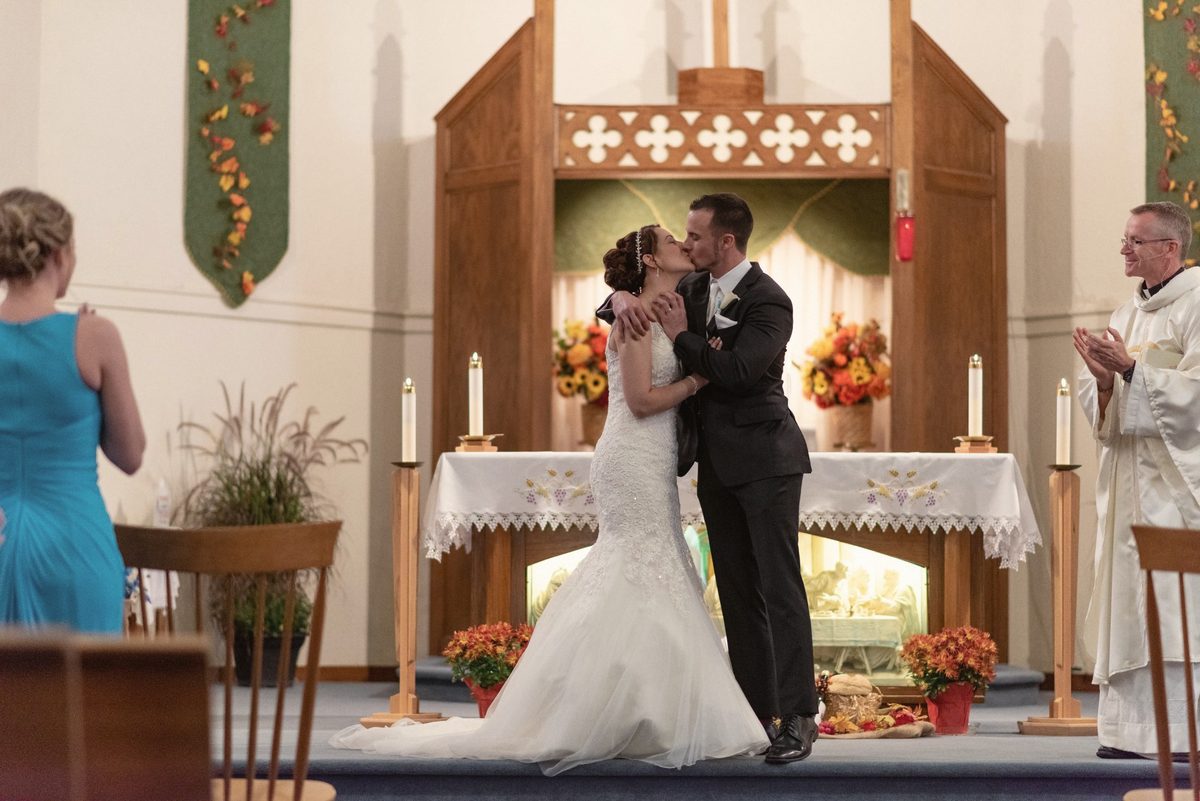 Bride and groom sharing their first kiss as a married couple at the altar
