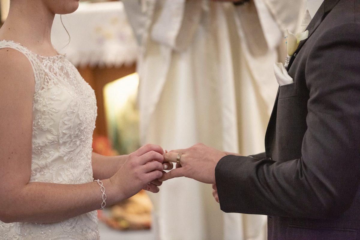 Close-up of the bride sliding the ring onto the groom's finger