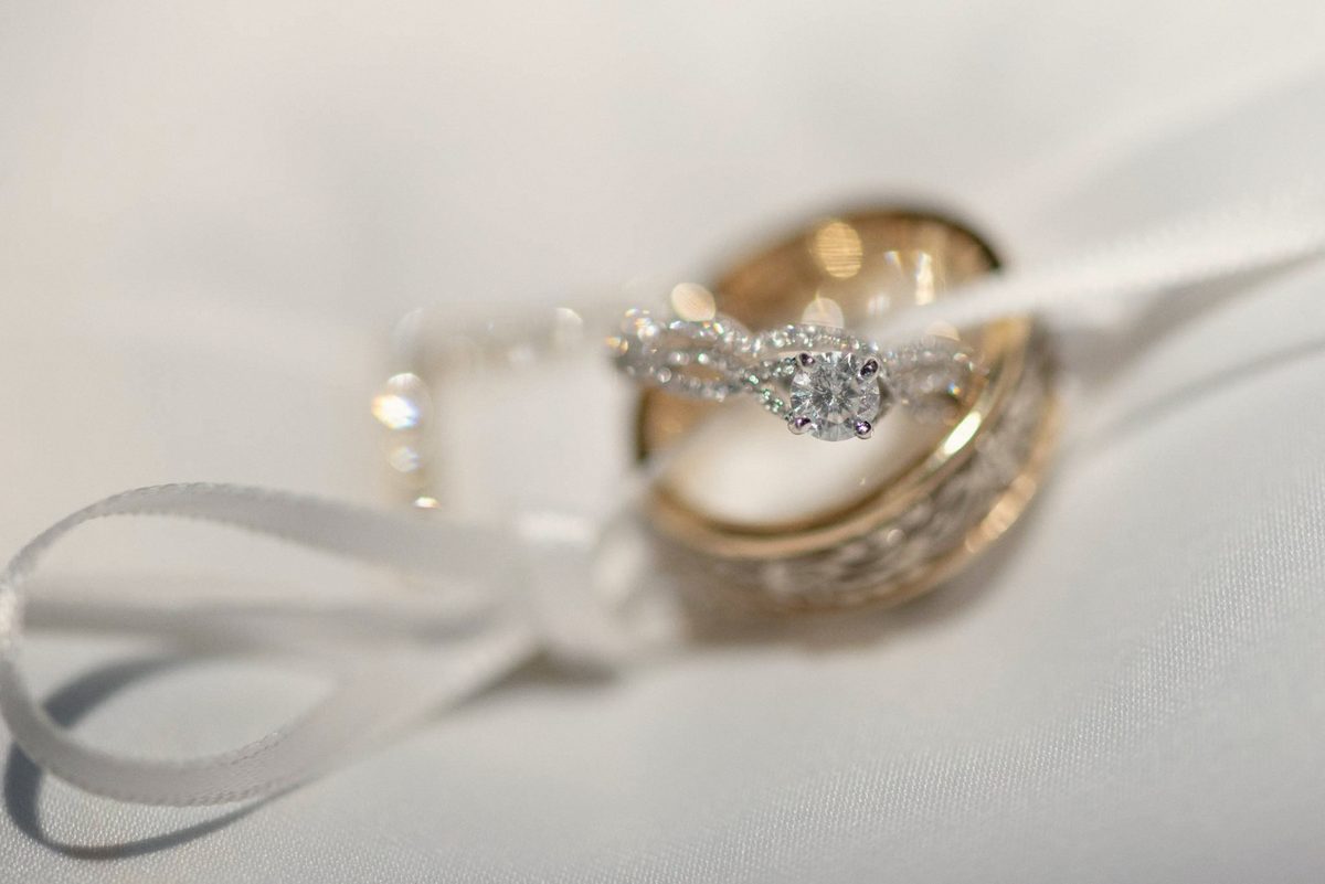 Wedding band and diamond engagement ring resting on a white satin ribbon