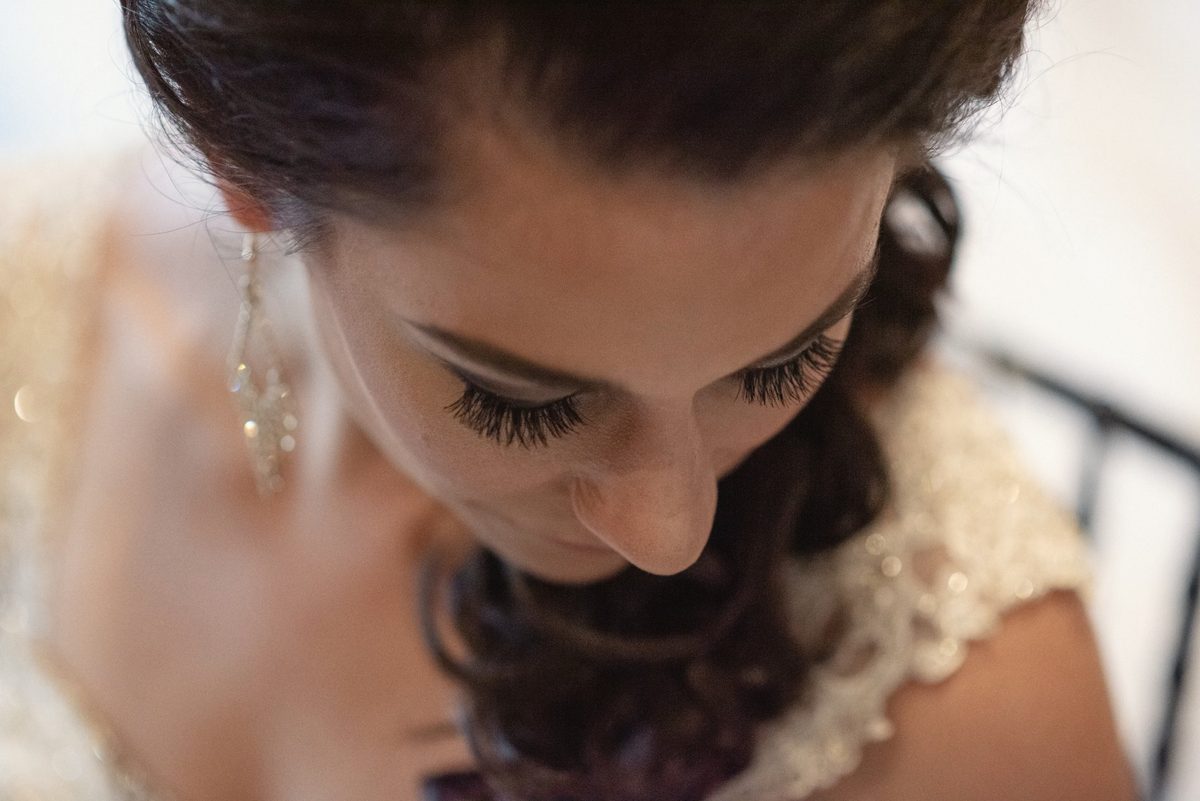 Close-up of the bride looking down, her lashes and lace neckline in view