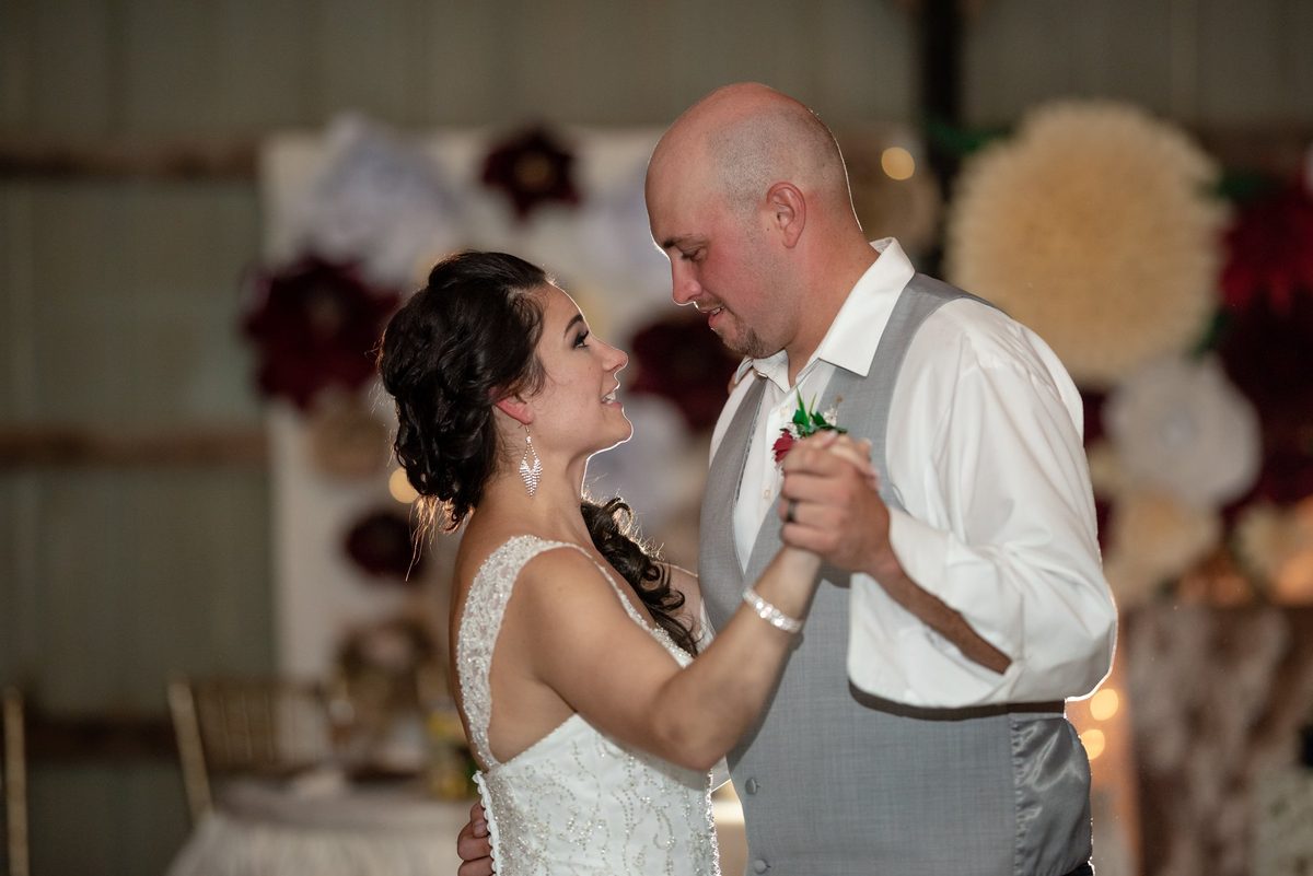 Bride sharing a dance with an older guest in front of a floral wall