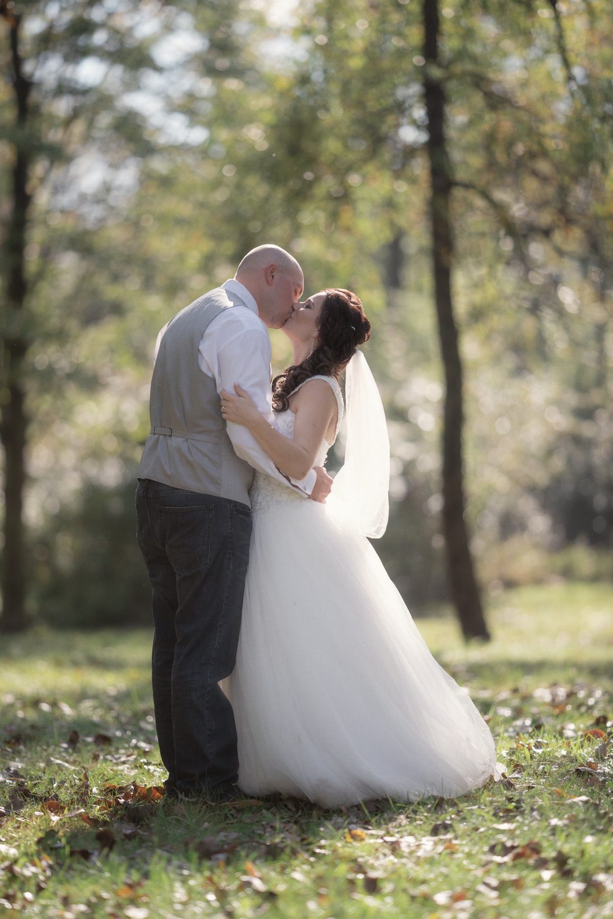 Bride and groom holding each other under tall trees