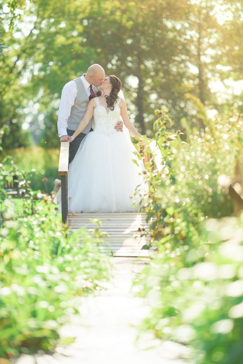 Bride and groom embracing at the end of a sunlit garden path