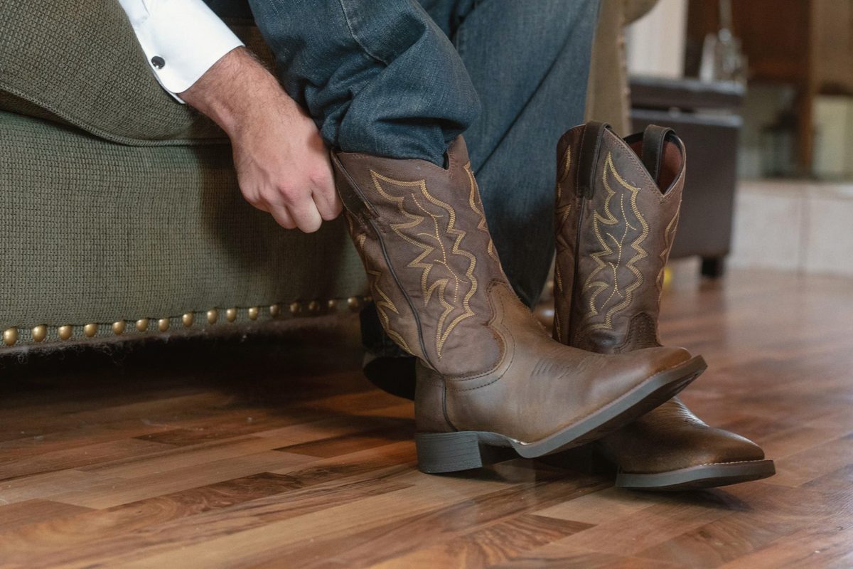 Groom pulling on his brown cowboy boots