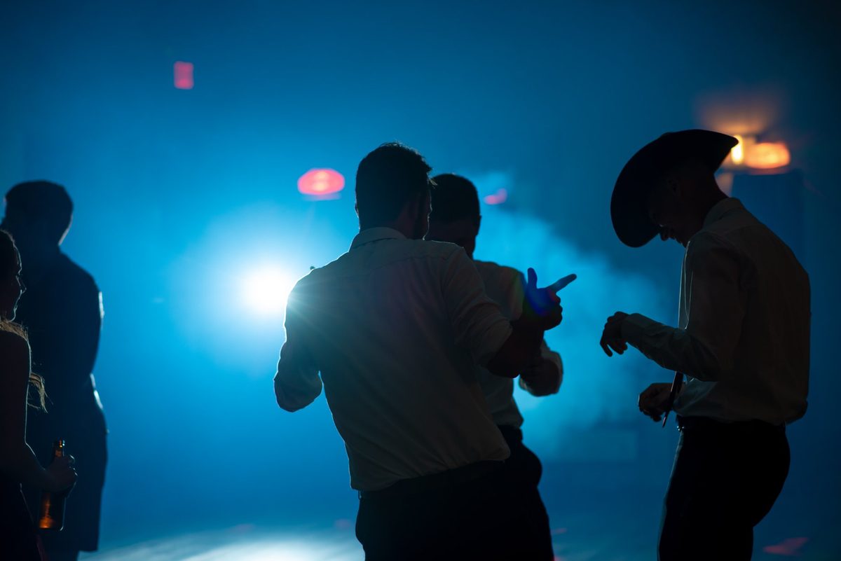 Guests dancing in silhouette against blue dance-floor lights and haze at Links of Kent