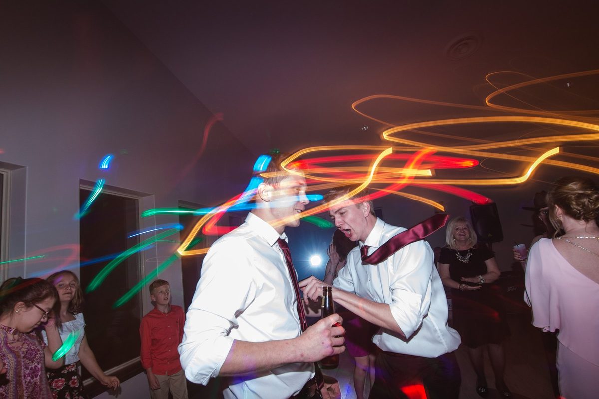 Guests dancing on the reception floor with colourful light trails swirling around them at Links of Kent