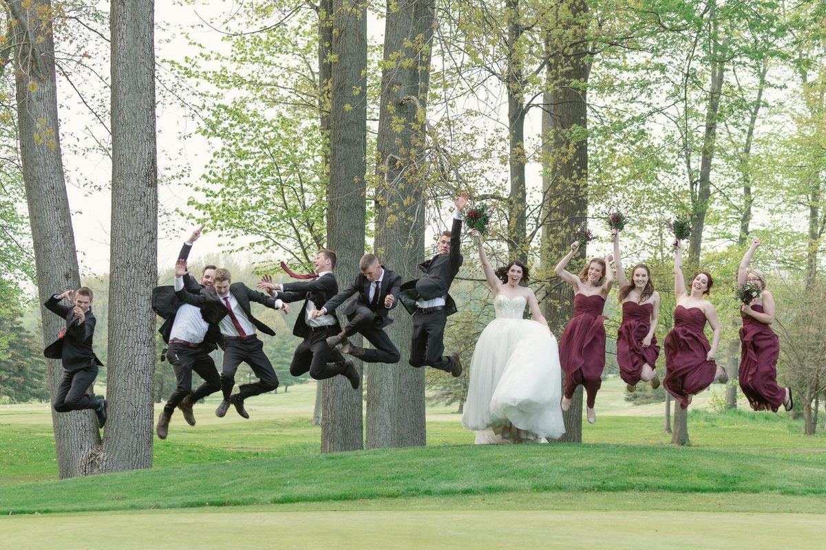 Wedding party jumping in the air among tall trees