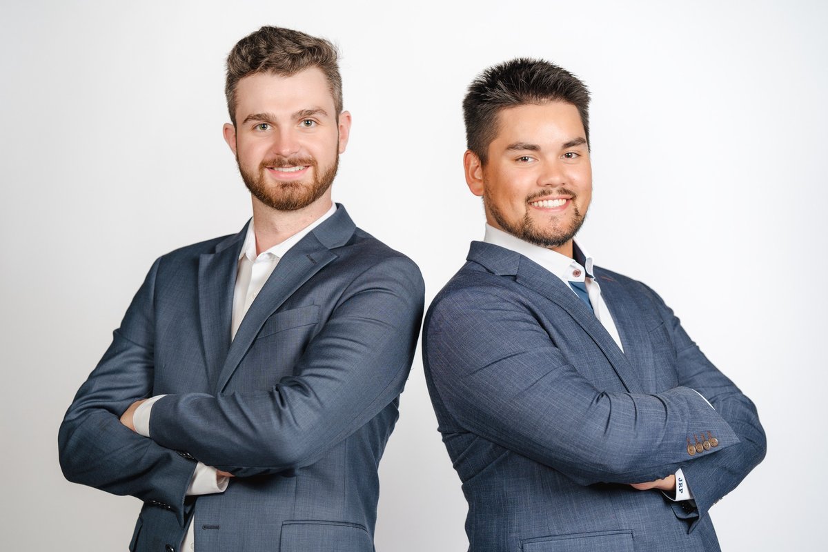 Two business partners in suits standing back to back with arms crossed against a white backdrop, a team photo from a professional headshot session in Chatham-Kent